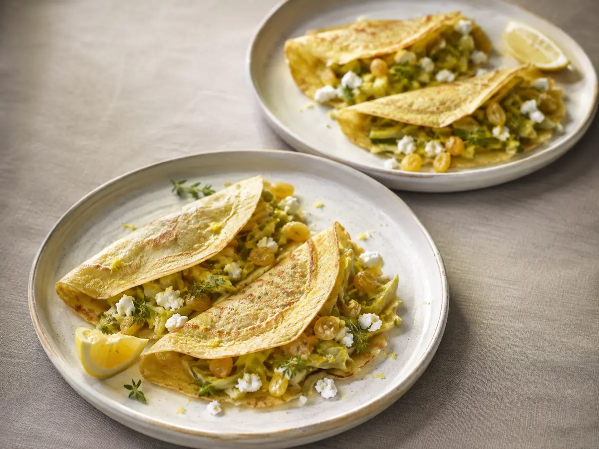 Crêpes de pois chiche garnies de poireaux, chèvre frais et raisins dorés